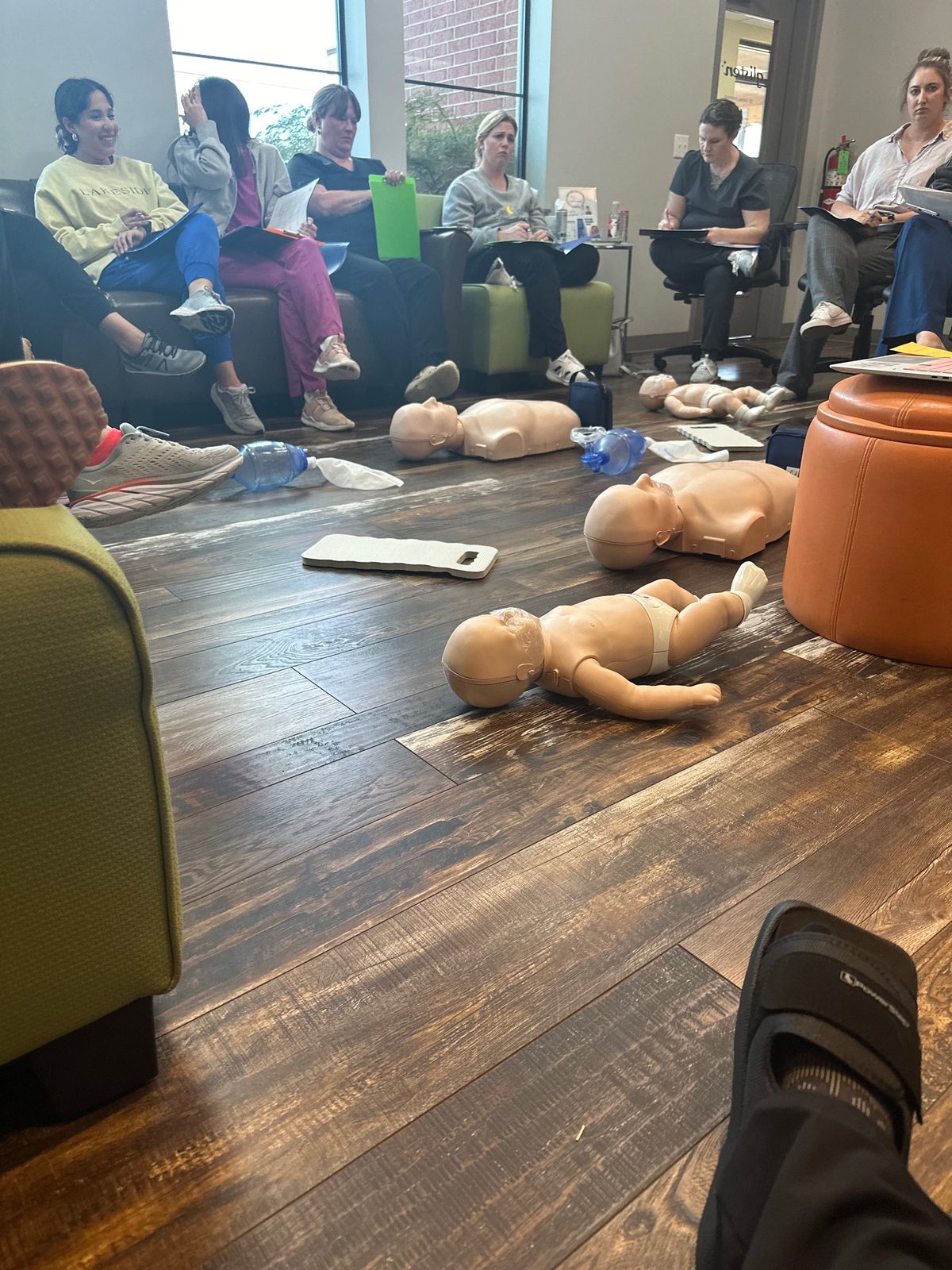 Students practicing hands-on CPR with manikins in a Brook Gibson training class